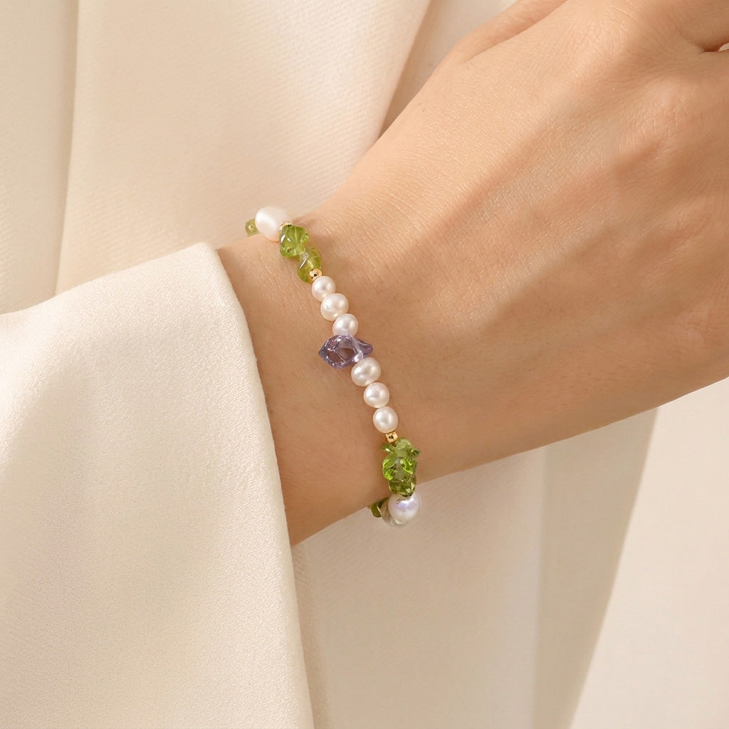 Bracelet with pearls and green beads on a wrist against a beige background