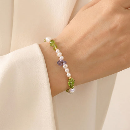 Bracelet with pearls and green beads on a wrist against a beige background