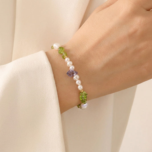 Bracelet with pearls and green beads on a wrist against a beige background