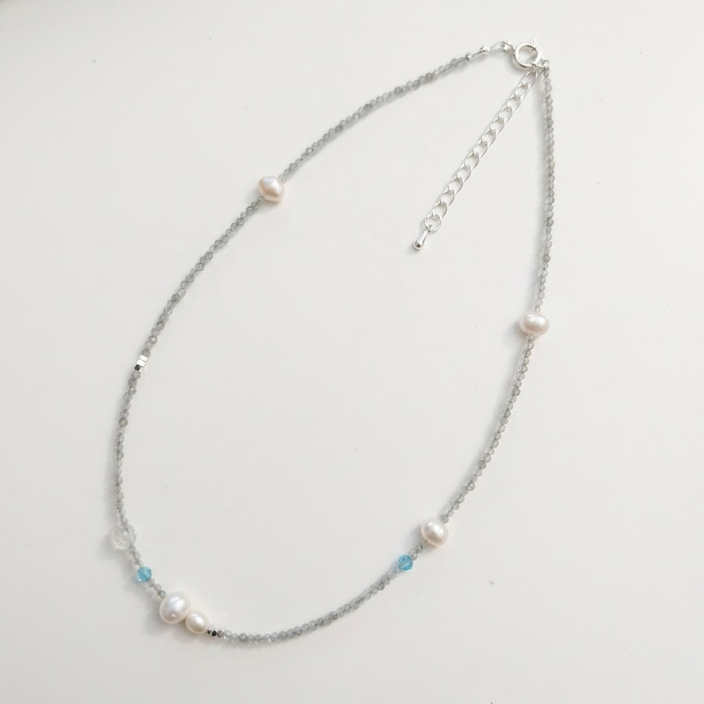 Close-up of genuine freshwater pearls, gray moonstone, and sparkling aquamarine crystals on a dainty silver choker