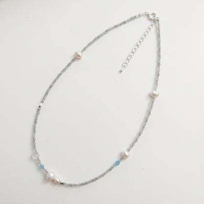 Close-up of genuine freshwater pearls, gray moonstone, and sparkling aquamarine crystals on a dainty silver choker