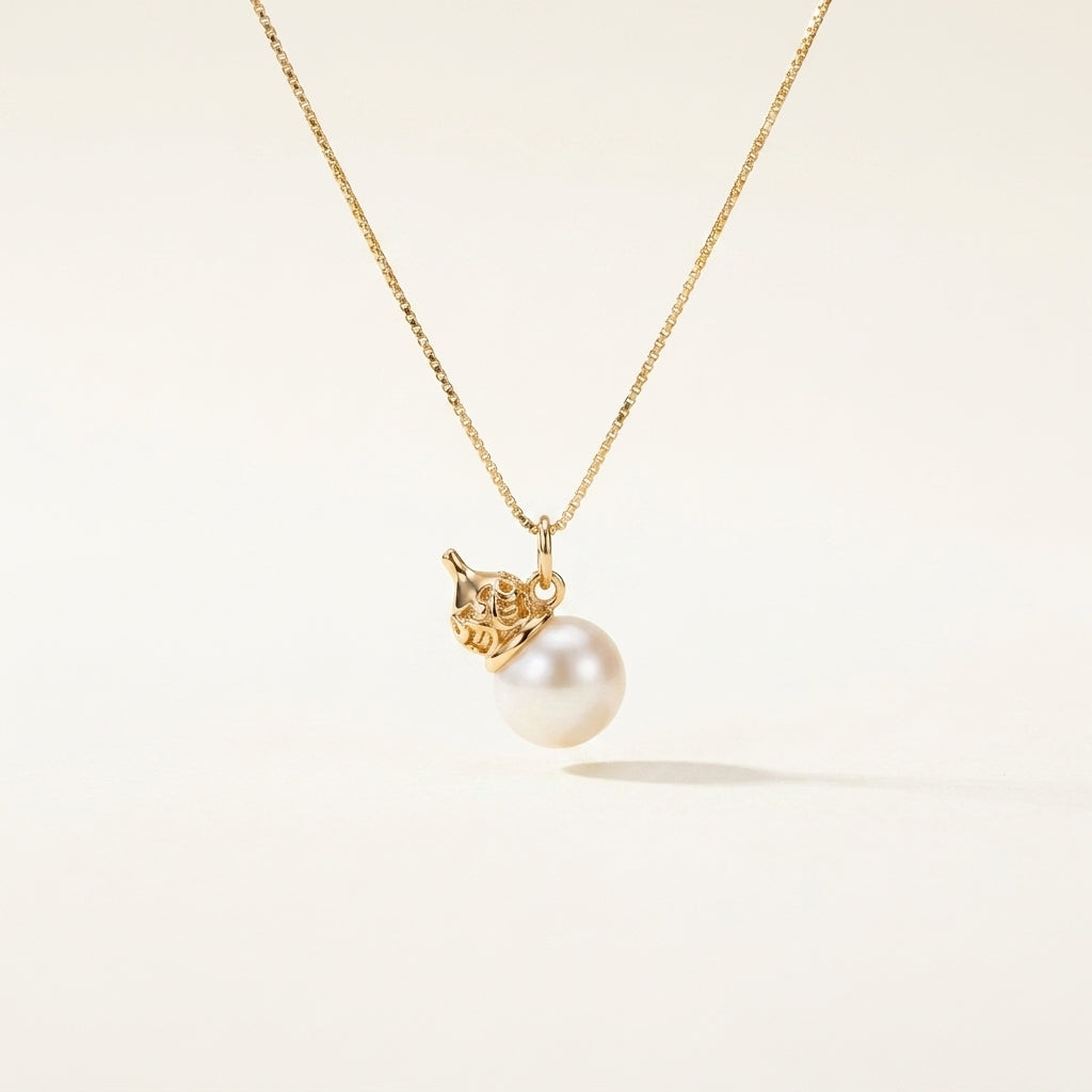 Gold necklace with a pearl pendant on a light beige background