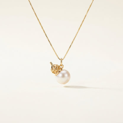 Gold necklace with a pearl pendant on a light beige background