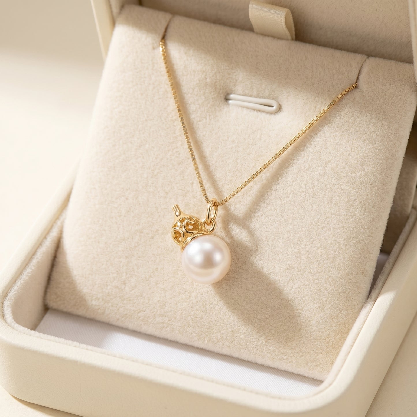 Delicate beaded necklace with a gold clasp in an open jewelry box.