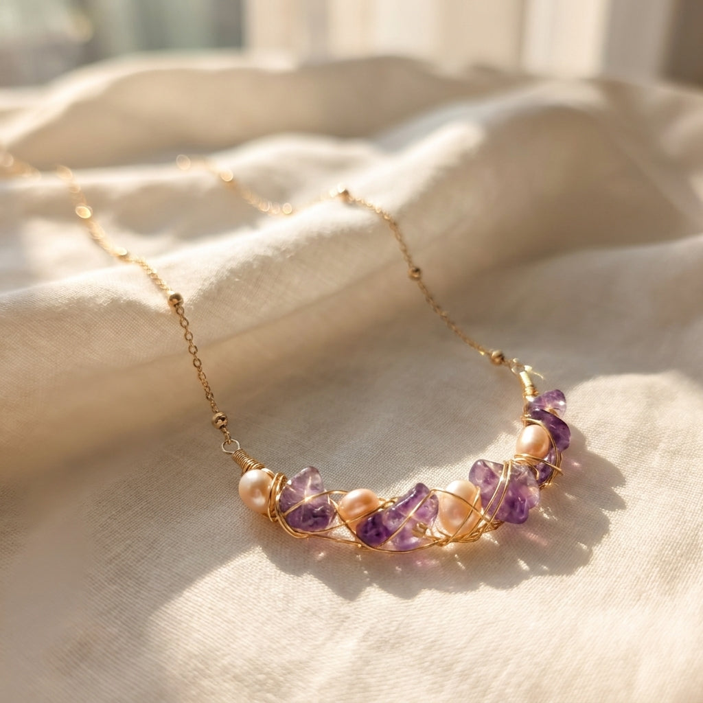 Delicate gold necklace with purple semi-precious stones and pearls laid flat.
