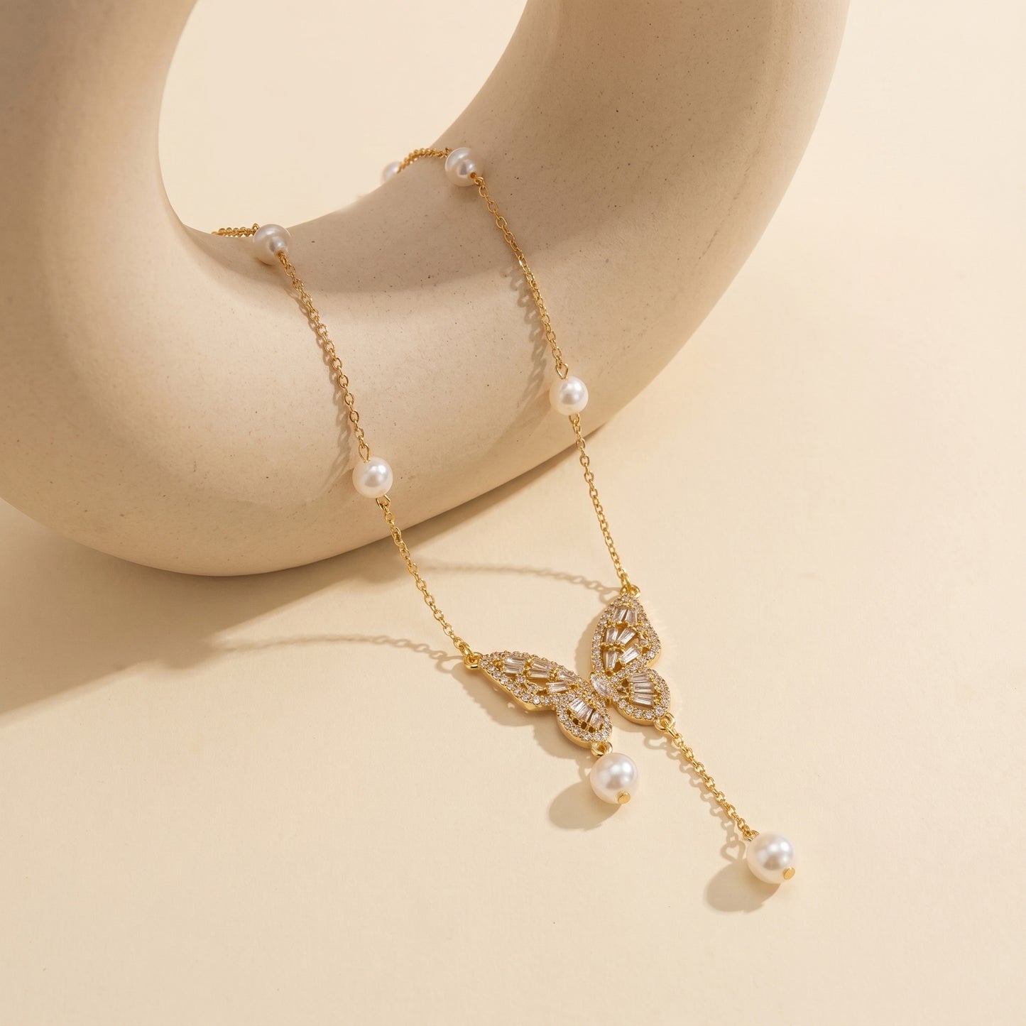 High-quality gold chain necklace featuring a delicate butterfly and natural pearl drop draped elegantly