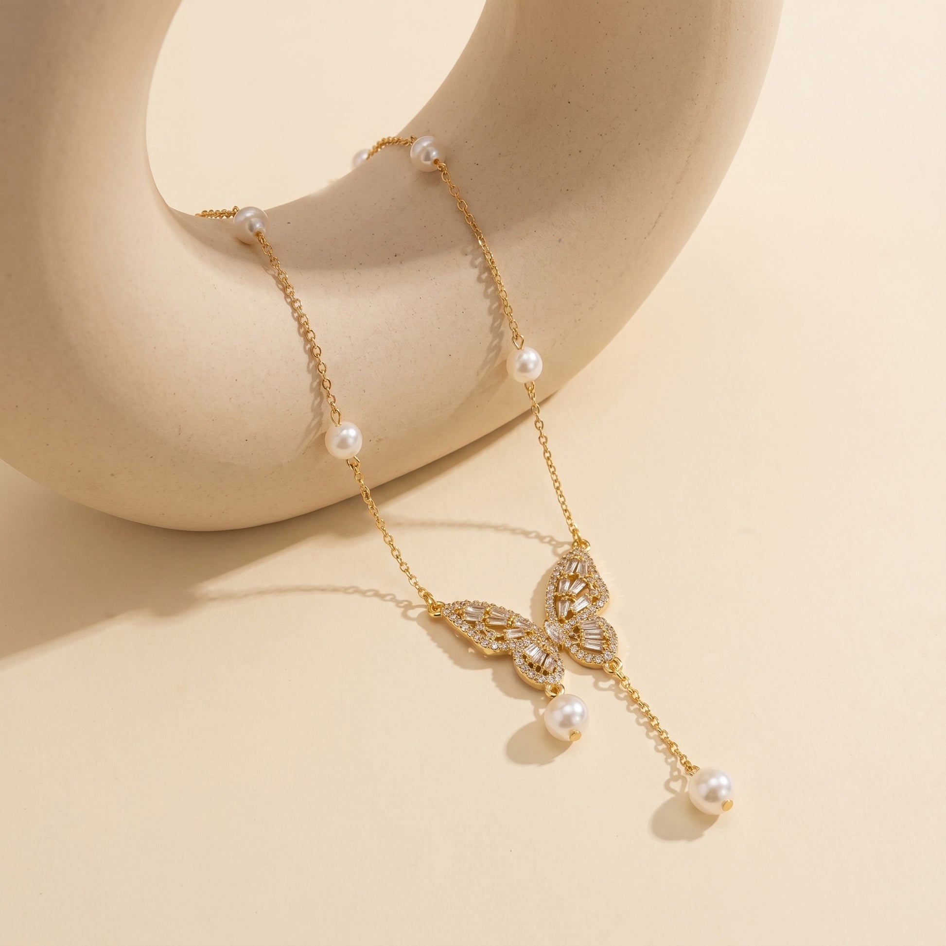 High-quality gold chain necklace featuring a delicate butterfly and natural pearl drop draped elegantly
