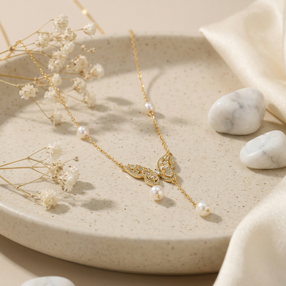 Minimalist gold-plated chain coiled to showcase the intricate butterfly pendant and statement pearl drop