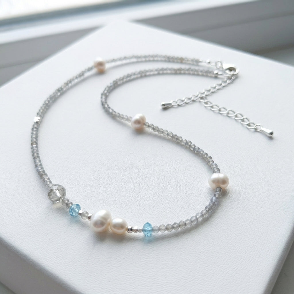 Necklace with pearls and blue beads on a white surface