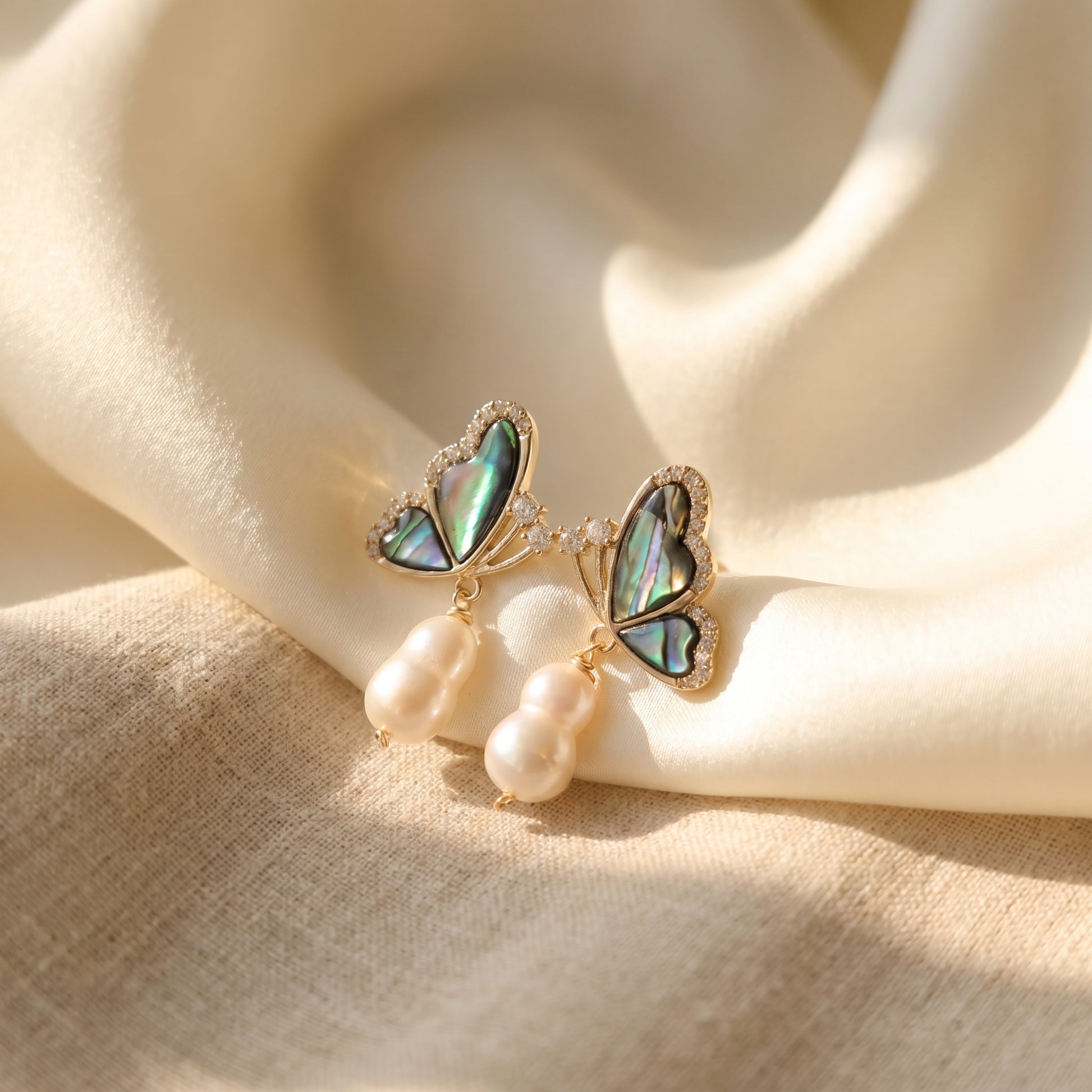 Elegant ocean-inspired abalone and baroque pearl drop earrings reflecting natural light.
