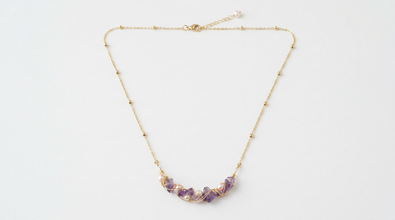Gold necklace with purple beads on a white background