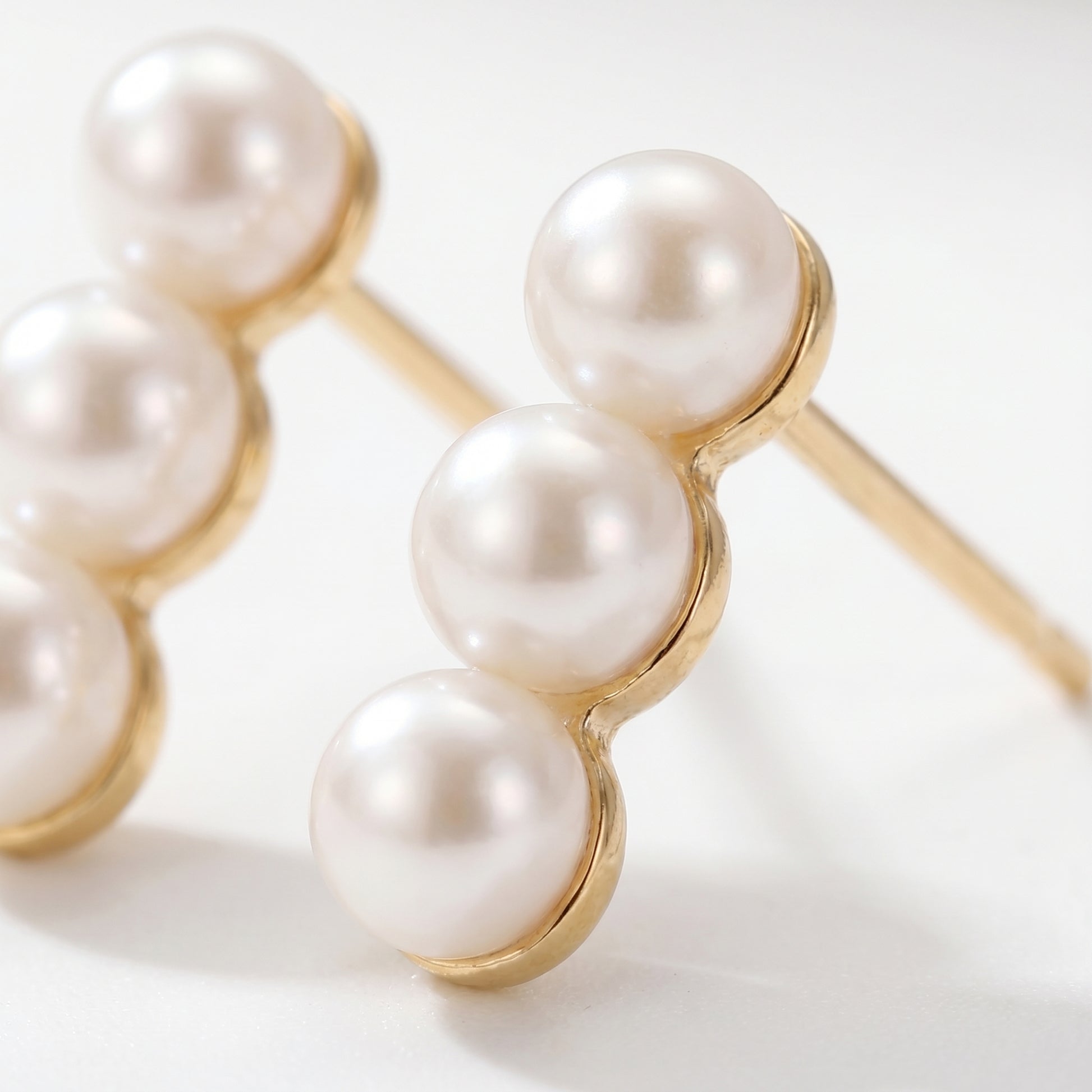 Macro detail shot highlighting the high-quality gold hardware and pure natural freshwater pearls of the Lumina Trio earrings.