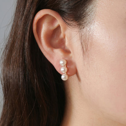 Model wearing the minimalist Lumina Trio pearl stud earrings in gold, side profile view.