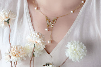 Detail view of the minimalist gold butterfly necklace with pearl resting on the collarbone, perfect bridal accessory