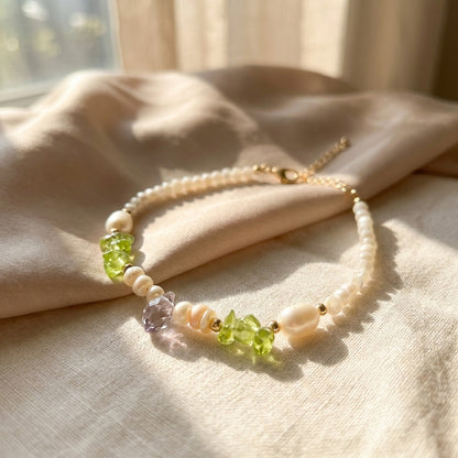 bracelet with pearls and green beads on a beige fabric background
