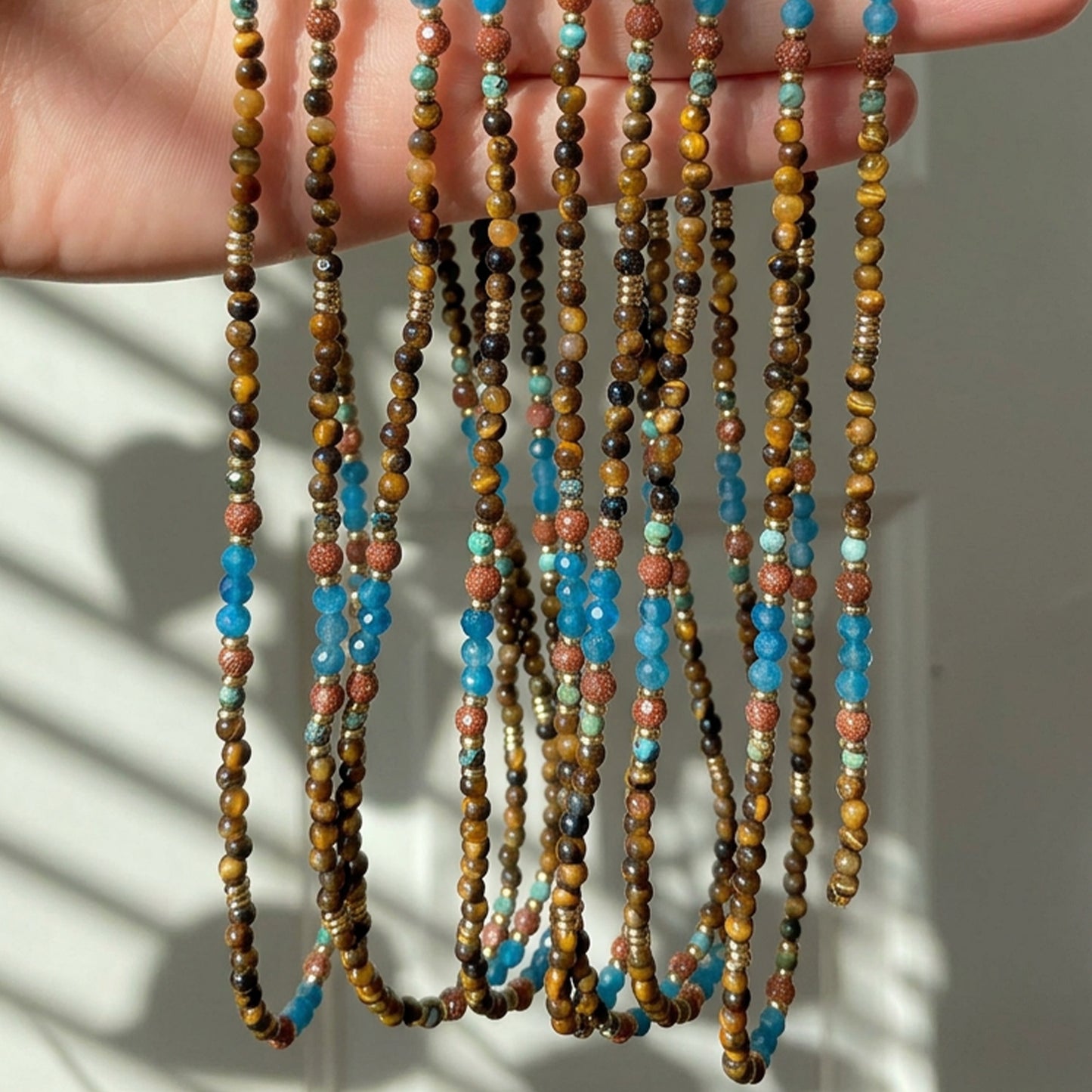 Terra Aura natural stone necklace curled on a light background, highlighting the earthy colors and 18K gold-plated accents.