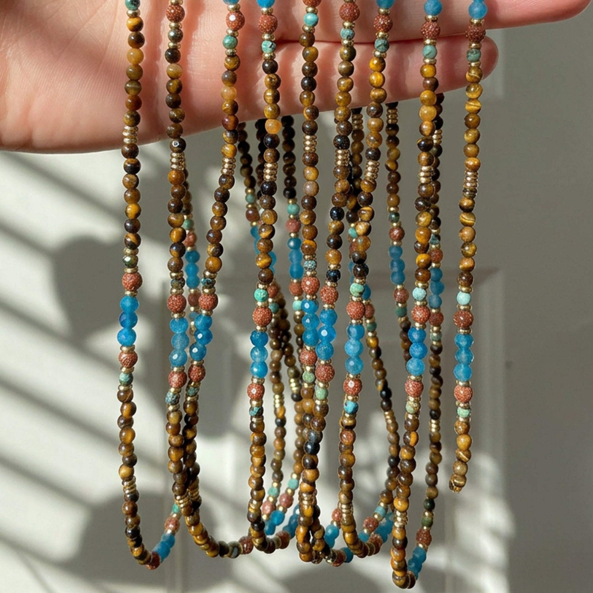 Terra Aura natural stone necklace curled on a light background, highlighting the earthy colors and 18K gold-plated accents.