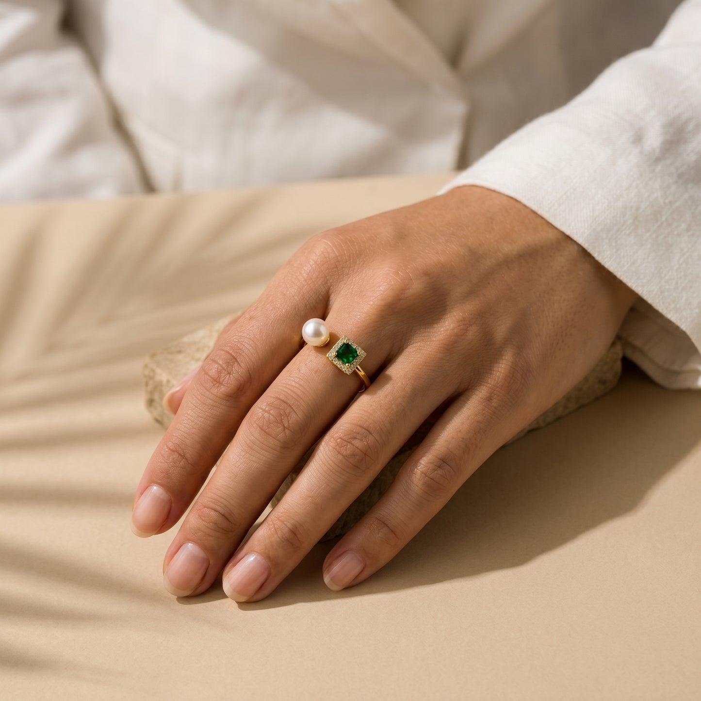 Woman wearing The 'Muse' emerald and pearl open ring styled effortlessly with a classic white shirt cuff.