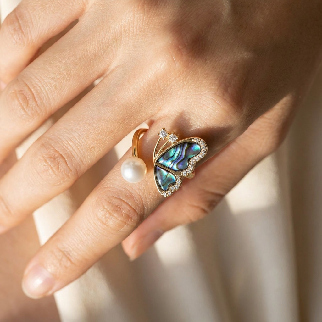 Model wearing the Aura Abalone Butterfly Ring in natural sunlight, showcasing the 14K gold open band, natural freshwater pearl, and iridescent shell wings by Whisperland Studio