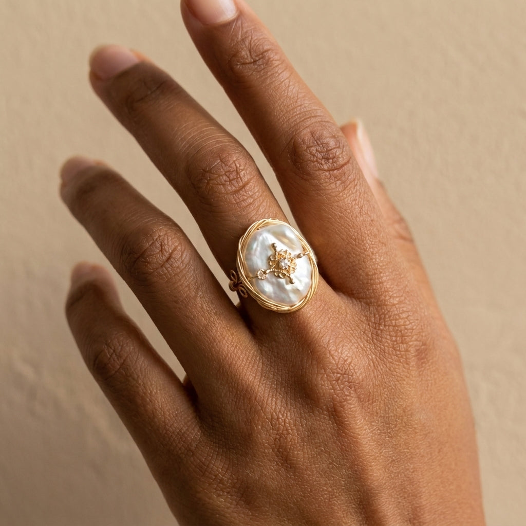 Model wearing The 'Aurelia' 14K gold plated baroque pearl ring while holding a string of pearls, capturing a romantic vintage aesthetic.