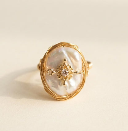 Two 'Aurelia' artisan wire wrapped baroque pearl rings displayed on a white stone, highlighting the unique organic shape of the natural pearls.