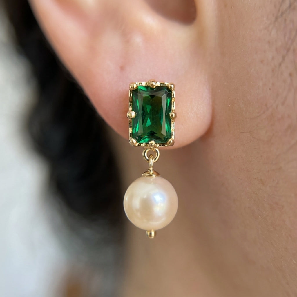 Close-up view of the “Eden’s Whisper” Emerald and Freshwater Pearl Drop Earrings showing the 14K gold detailed setting on the ear