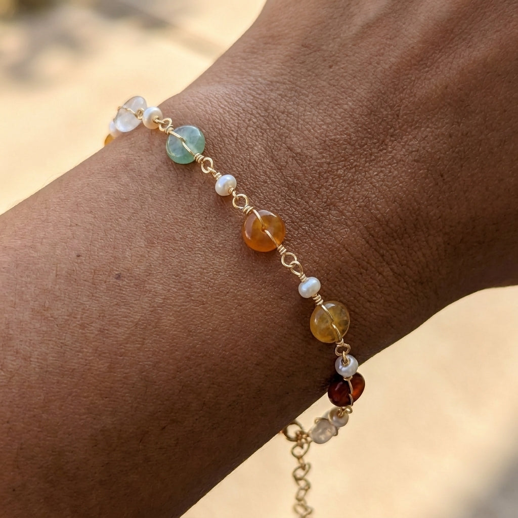 A hand wearing the minimalist Elara freshwater pearl and green aventurine bracelet resting against a soft tan background, showcasing everyday wear.