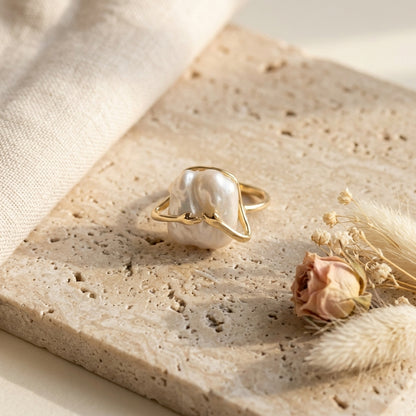 Model wearing The 'Embrace' 14K gold plated open band ring, showcasing the intricate hands cradling the organic baroque pearl.