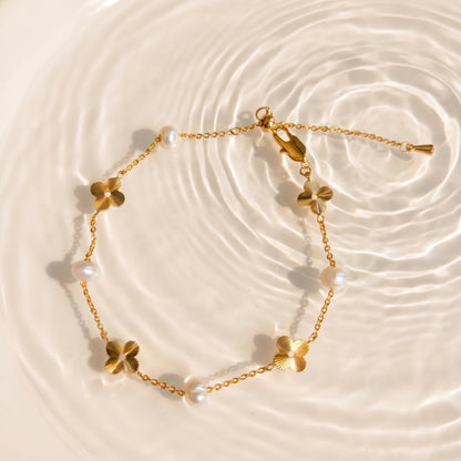 Flat lay of the Flora Whisper gold and pearl bracelet gently coiled on a creamy linen texture.