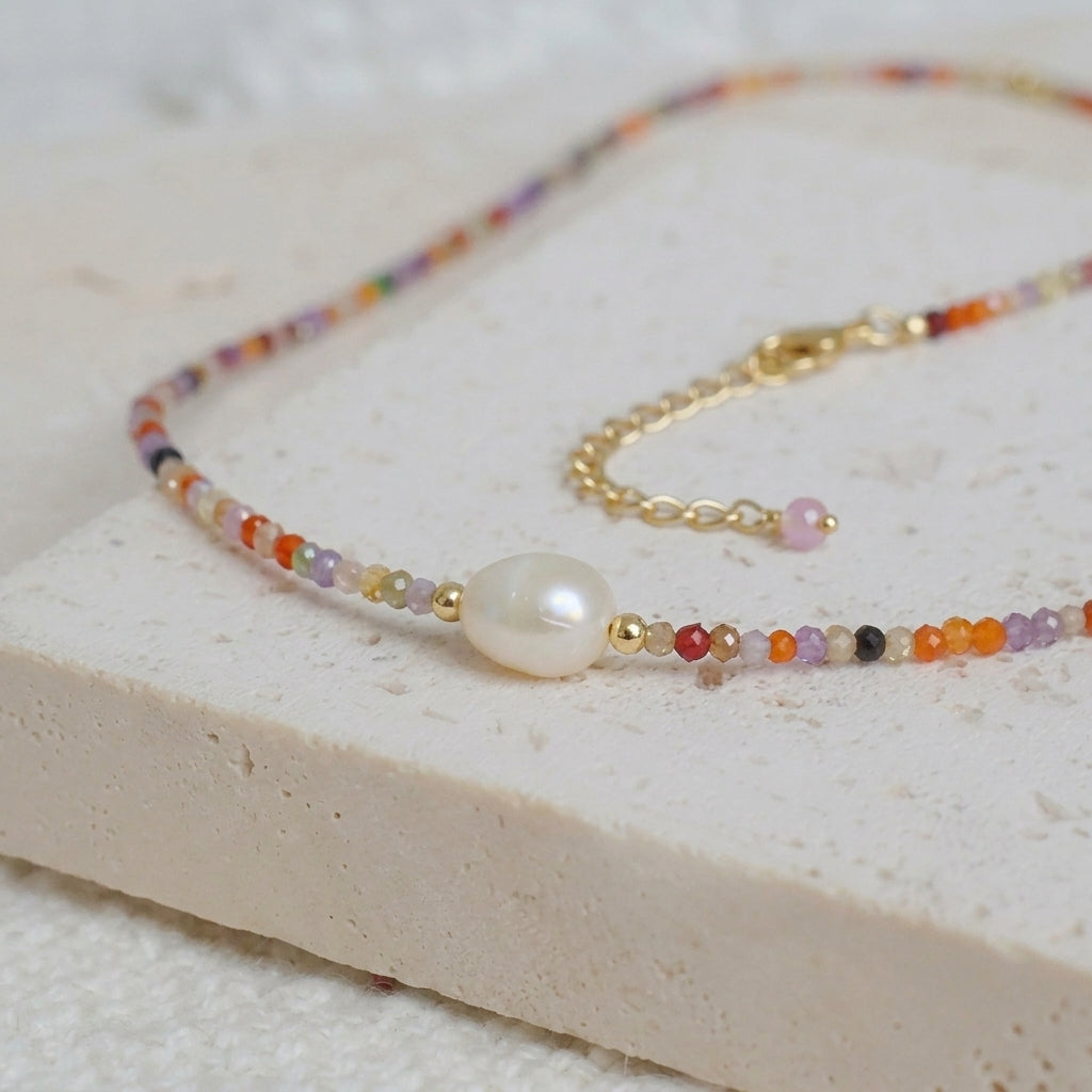 Detailed shot of handcrafted zircon beads and a genuine luminous freshwater pearl on a fine gold chain.