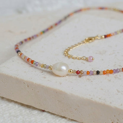Detailed shot of handcrafted zircon beads and a genuine luminous freshwater pearl on a fine gold chain.