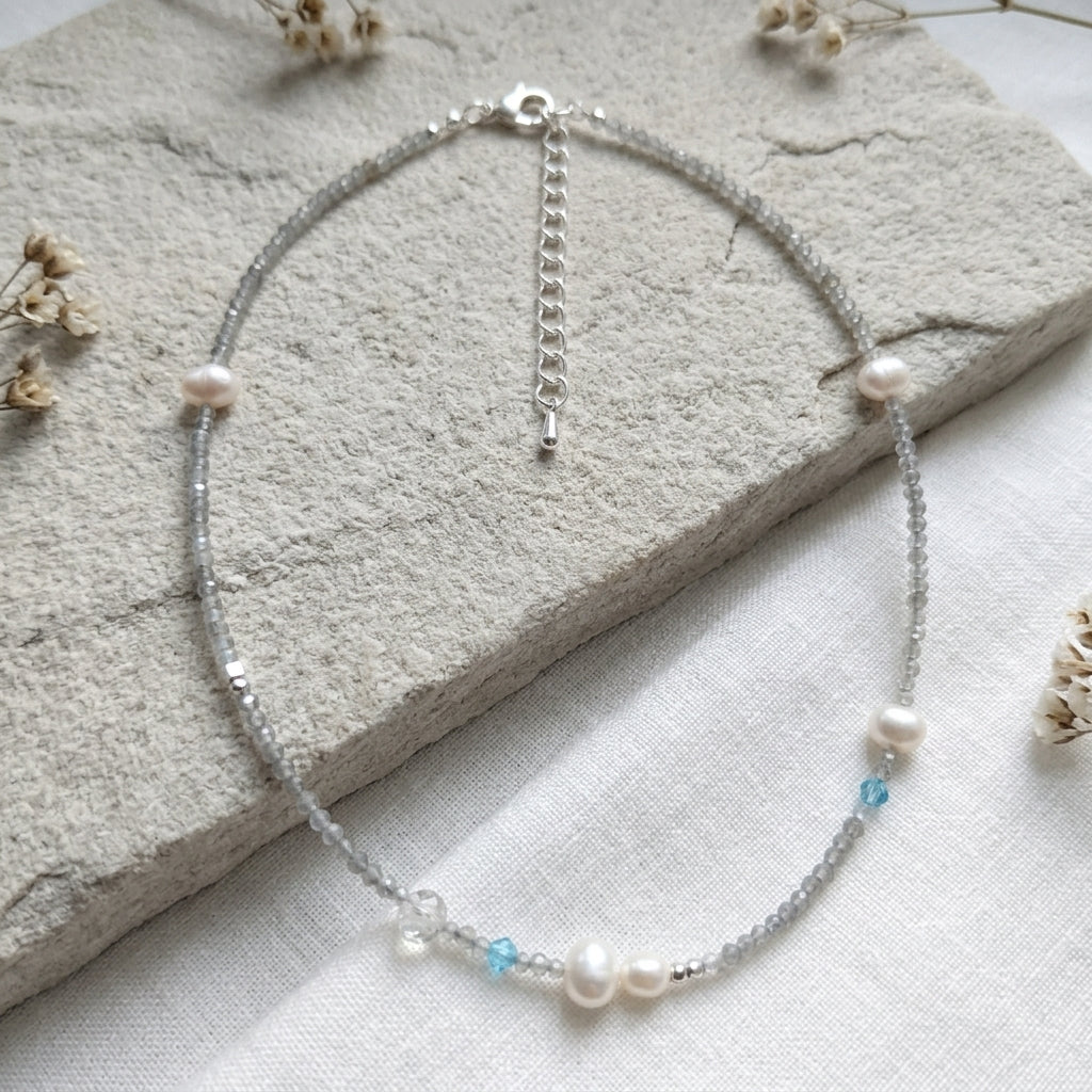 Silver necklace with pearls and blue beads on a stone surface