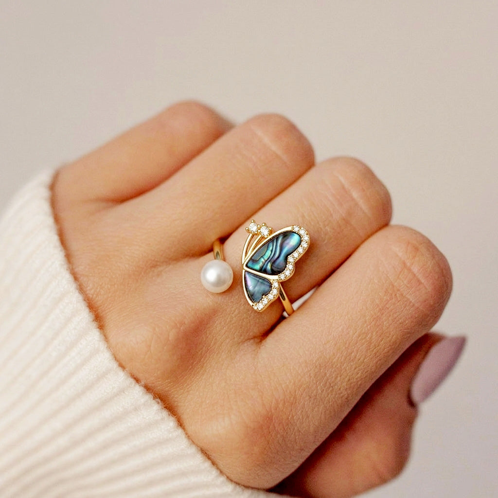 Macro shot of the iridescent butterfly wings and lustrous white pearl on a dainty gold ring