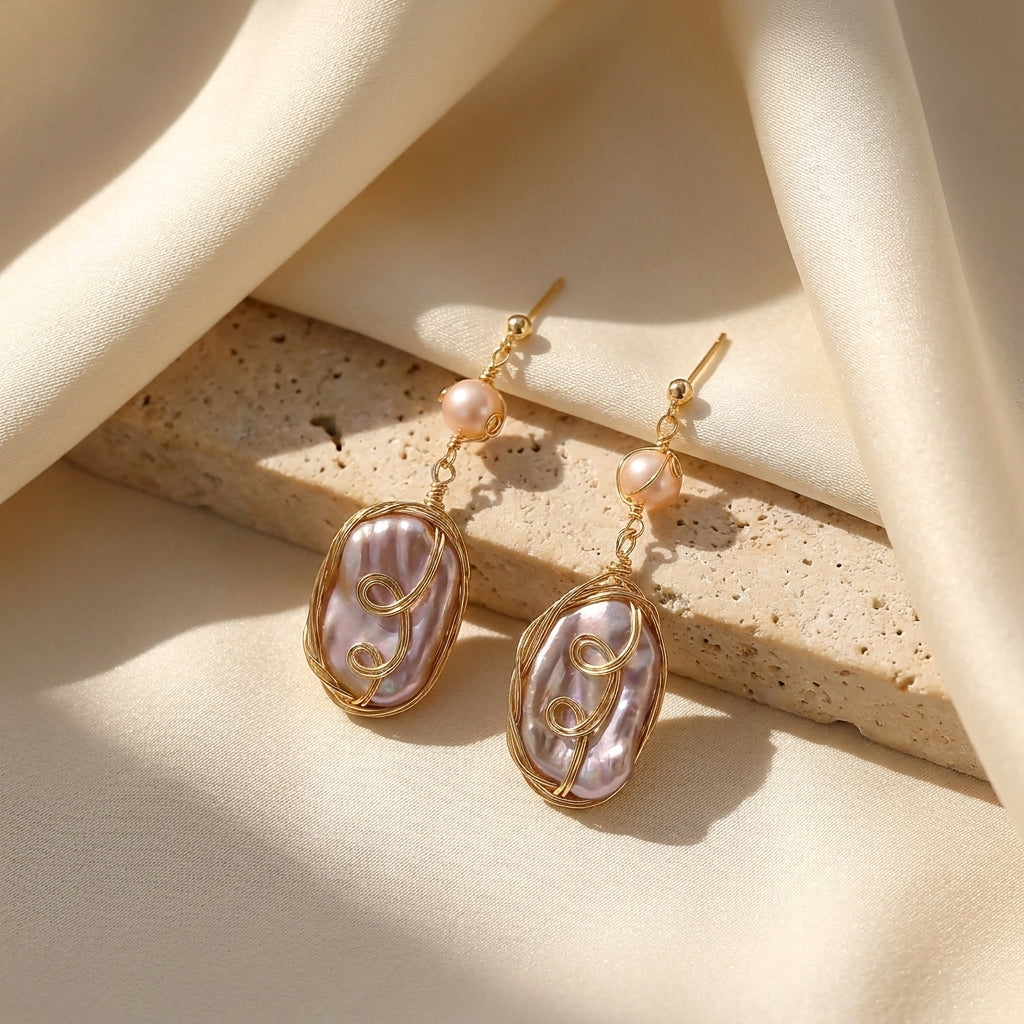 Macro detail shot of the classic round pearl and iridescent purple oval gemstone in a gold-plated setting.
