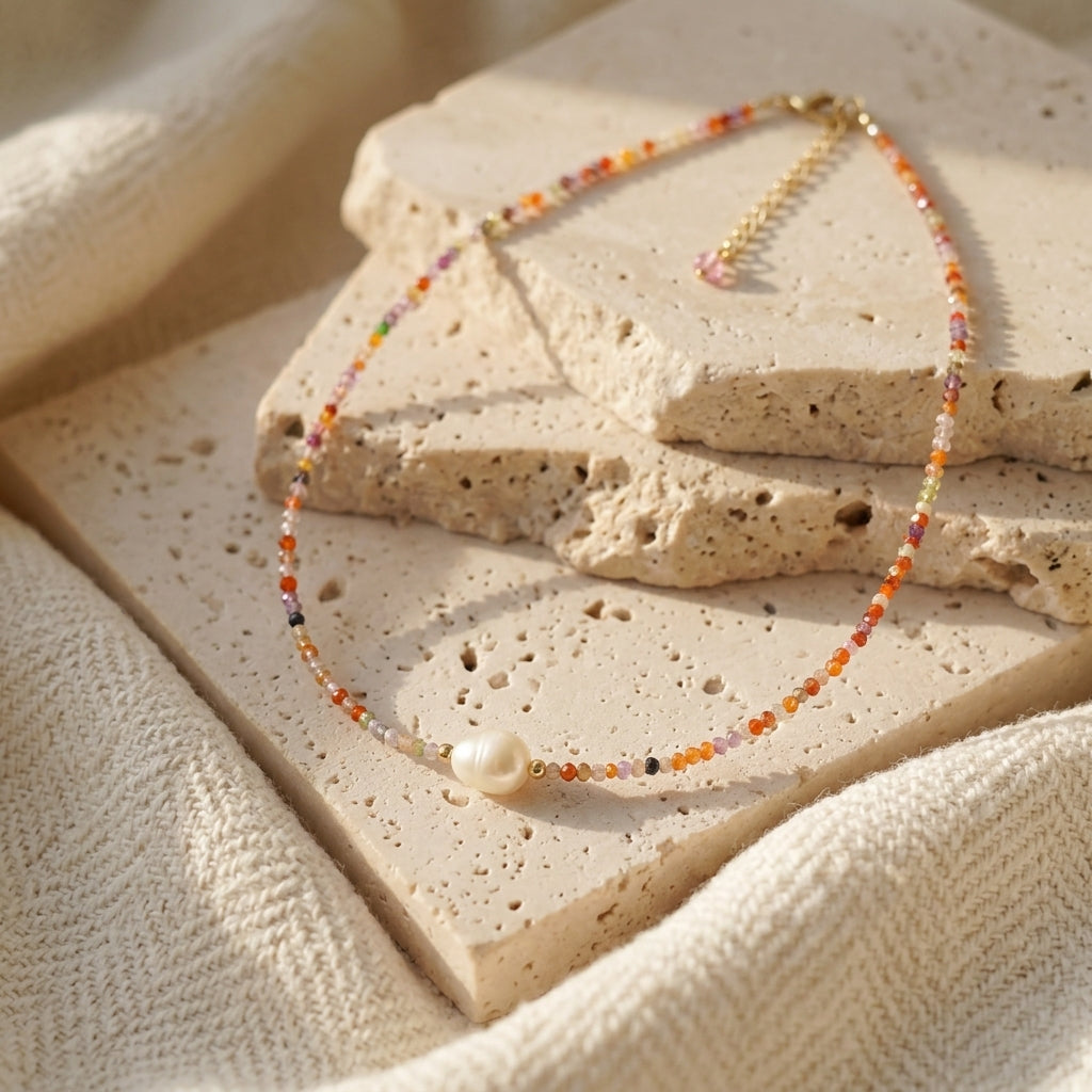 Minimalist colorful beaded pearl necklace displayed on a natural stone prop for a light and airy aesthetic.