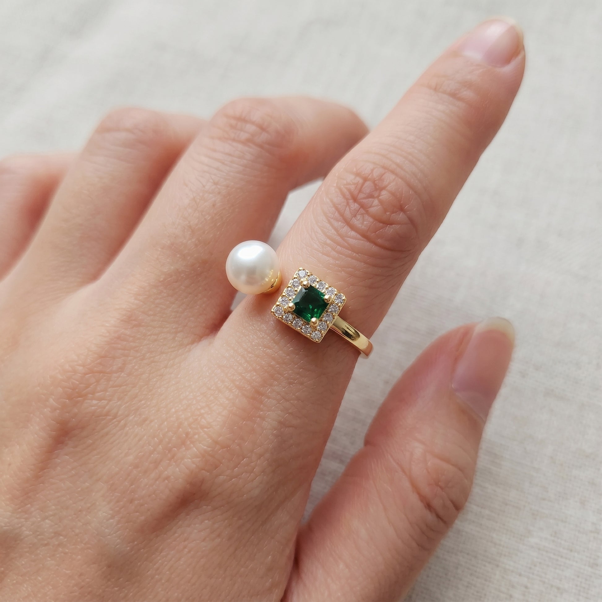 The 'Muse' emerald and pearl ring styled on a hand, perfect for everyday minimalist luxury.