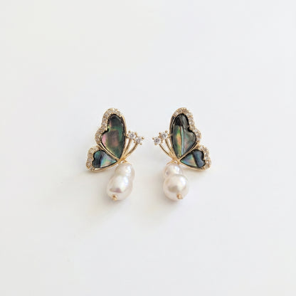 A pair of minimalist dangle earrings featuring natural baroque freshwater pearls and abalone butterfly tops.