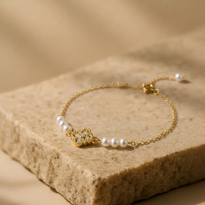 Aurelia natural freshwater pearl and gold bracelet worn outdoors with green foliage in the background, showing everyday styling.