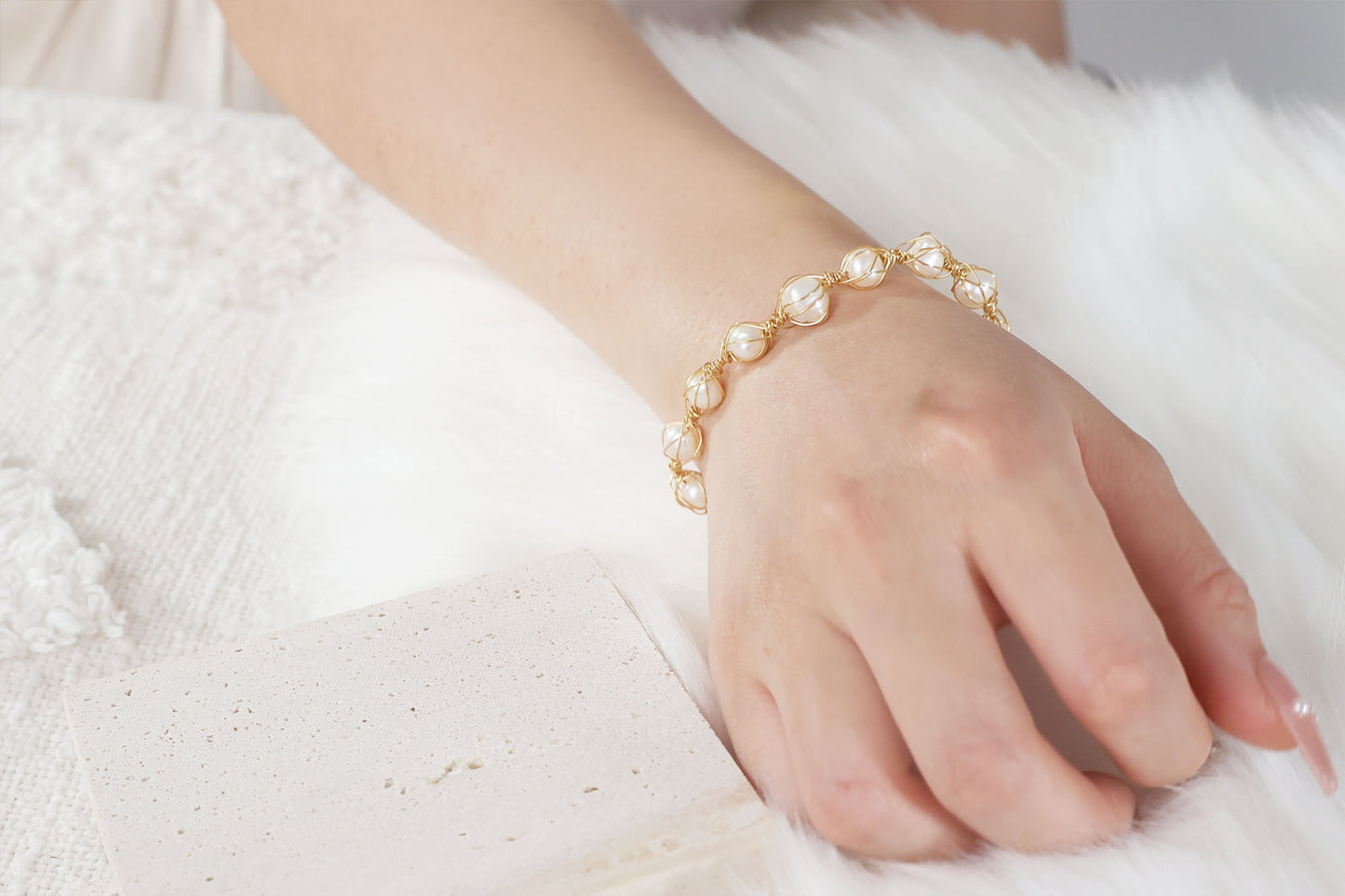 A woman's wrist wearing The Seraphina Handmade Freshwater Pearl Wire Wrapped Gold Bracelet