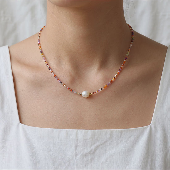 Video showcase of a model wearing the Sunrise Whisper dainty colorful beaded necklace with a central freshwater pearl, styled with a white square-neck top by Whisperland Studio.