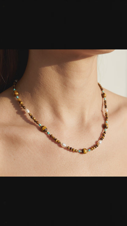 Video of model wearing Tierra choker with natural tiger's eye, turquoise, and natural baroque pearls in warm light.