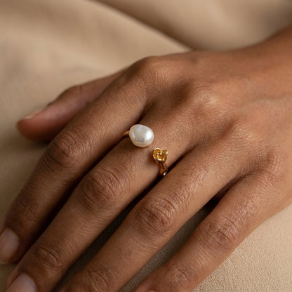 Model wearing the dainty 'Rosalie' baroque pearl and rose ring while delicately holding a loose pearl, emphasizing the romantic vintage style.