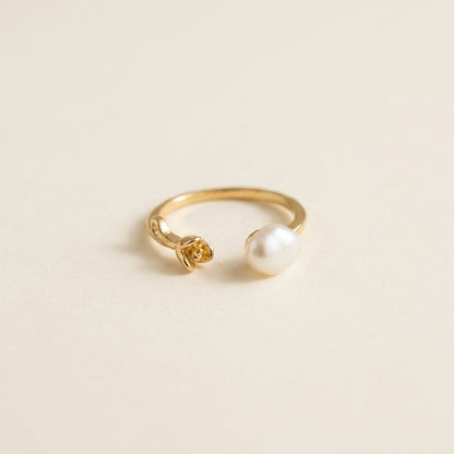 Two 'Rosalie' baroque pearl rose rings displayed elegantly on a textured stone prop, highlighting the 14K gold plated open band.