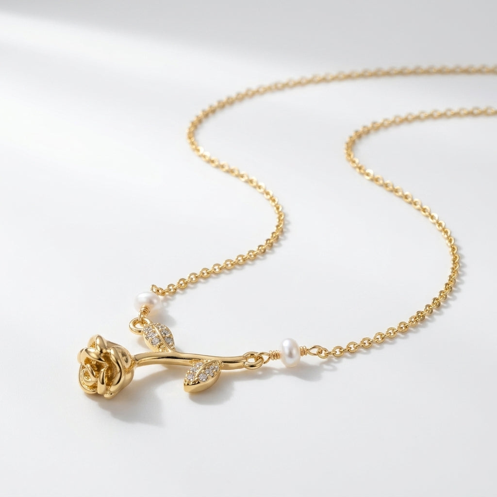 A gold necklace featuring a rose-shaped pendant with small clear stones and white pearl accents, displayed on a clean white background.