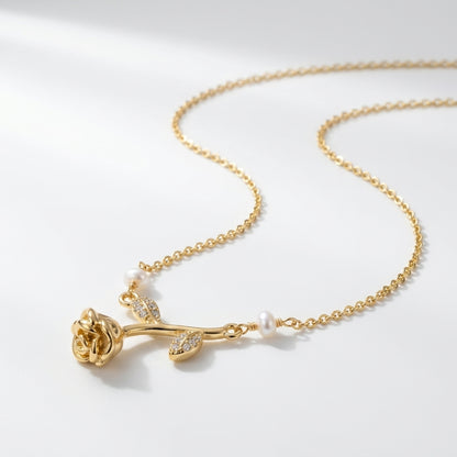 A gold necklace featuring a rose-shaped pendant with small clear stones and white pearl accents, displayed on a clean white background.