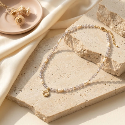 Detailed view of the purple crystal and pearl beaded choker necklace with a dangling gold smiley face charm, displayed on a prop.