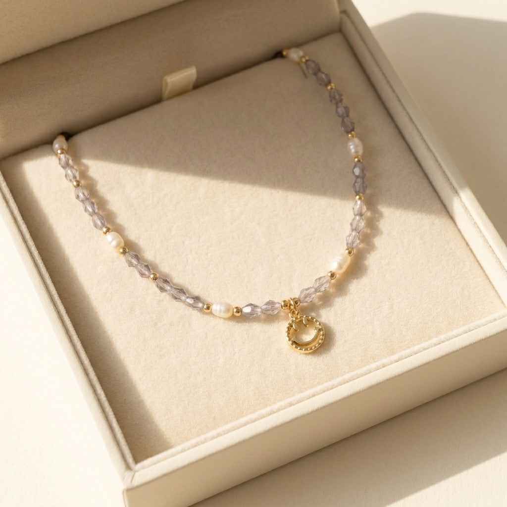 Aesthetic display of the 'Serotonin' dainty smiley face necklace on a stone textured prop, highlighting the purple and gold tones.