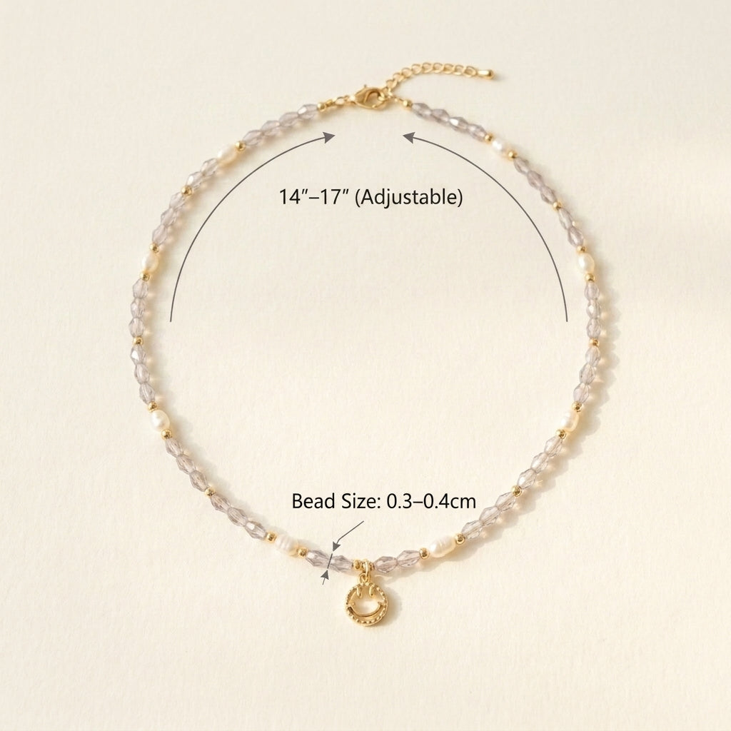 Close-up flat lay of the 'Serotonin' necklace, showing the texture of faceted purple crystals, lustrous pearls, and the shiny 14K gold-plated smiley face.