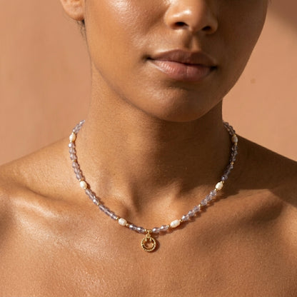 Dainty freshwater pearl and purple crystal beaded choker necklace with a gold smiley face charm, styled on a model.