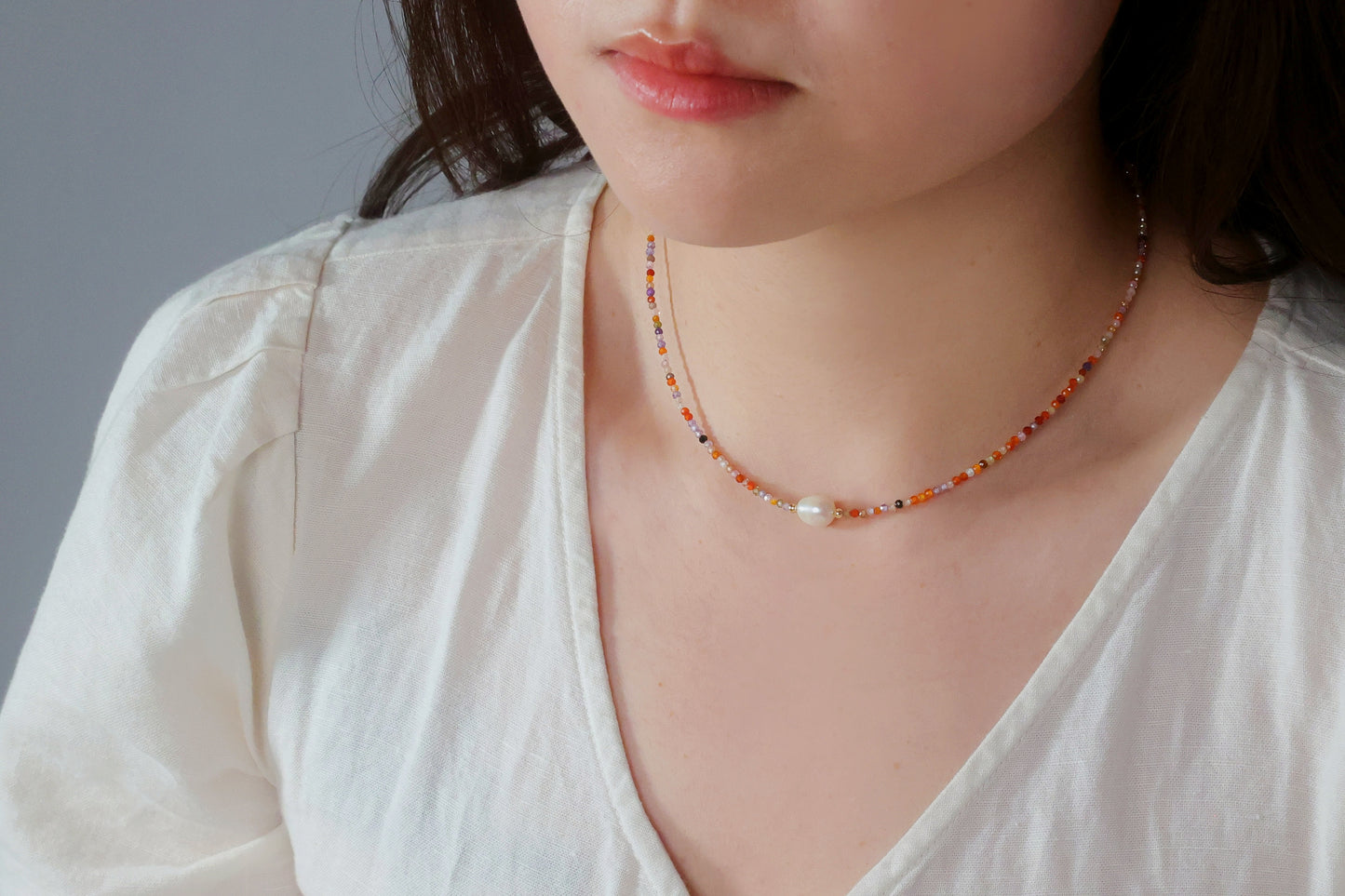 Model wearing the Sunrise Whisper dainty colorful beaded necklace with a white top, showcasing it as a versatile everyday accessory by Whisperland Studio.